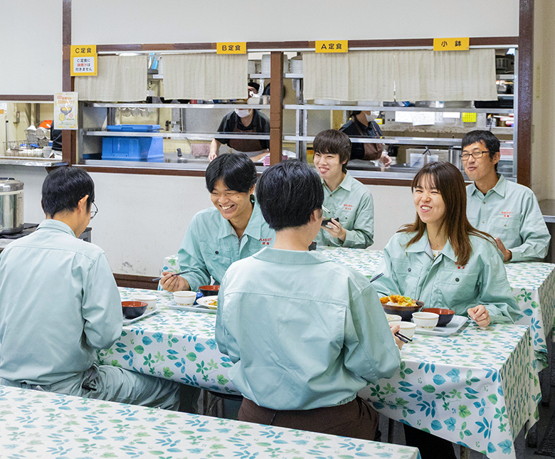 笑顔で手を振りながらマングローブの苗を植えている社員たち